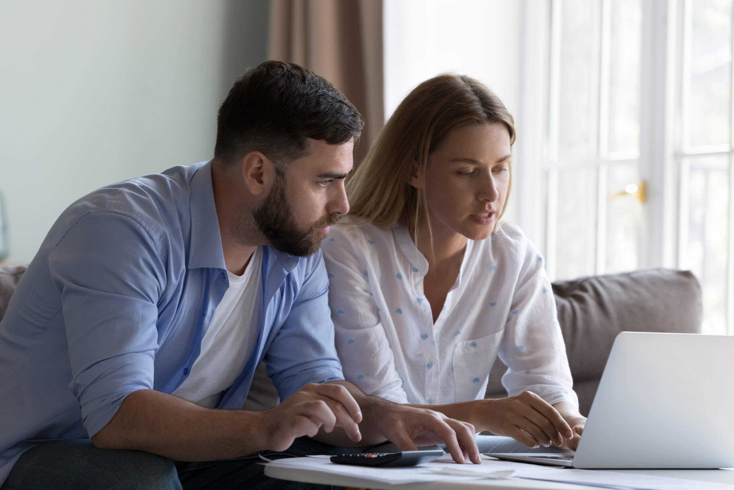 Couple reviewing tax documents together on a laptop at home